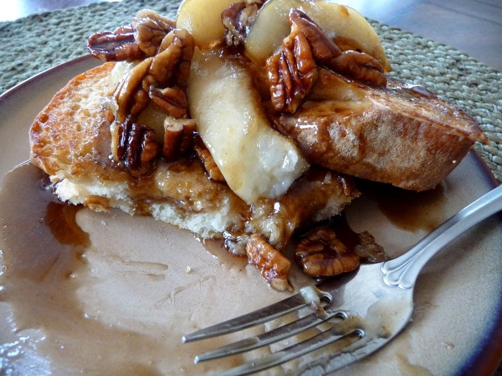 A plate of partially eaten pear and pecan french toast.