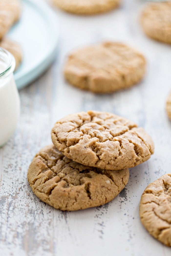 a stack of almond butter cookies on a white wooden table