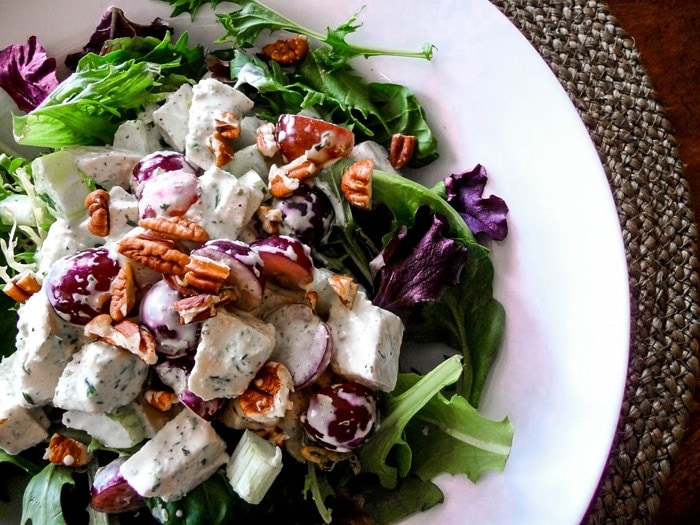 tarragon chicken salad served on a bed of greens on a white plate