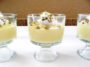 Three glass dishes filled with homemade white chocolate pudding and garnished with pistachios and whipped cream.