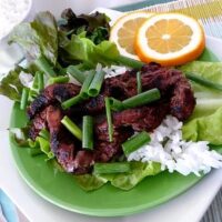 A Korean beef bulgogi lettuce wrap on a green plate.