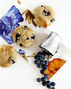 Overhead view of three blueberry cream cheese muffins with an overturned pail of blueberries.