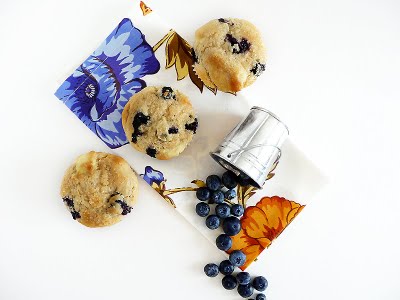 Overhead view of three blueberry cream cheese muffins with an overturned pail of blueberries.