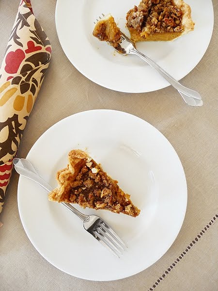 A slice of pumpkin pie with pecan topping on a white plate.