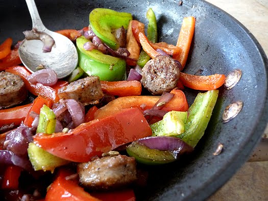 Sautéed Italian sausage, bell peppers and onion in a skillet. 