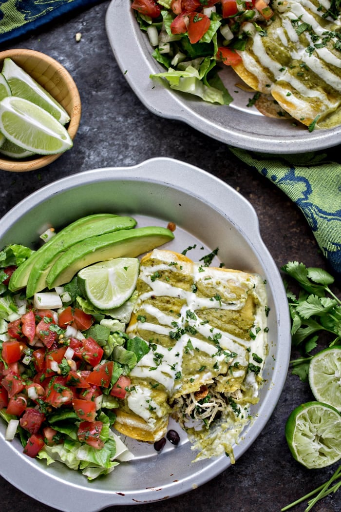 spinach enchiladas in round pan, drizzled with sour cream and tomatillo sauce