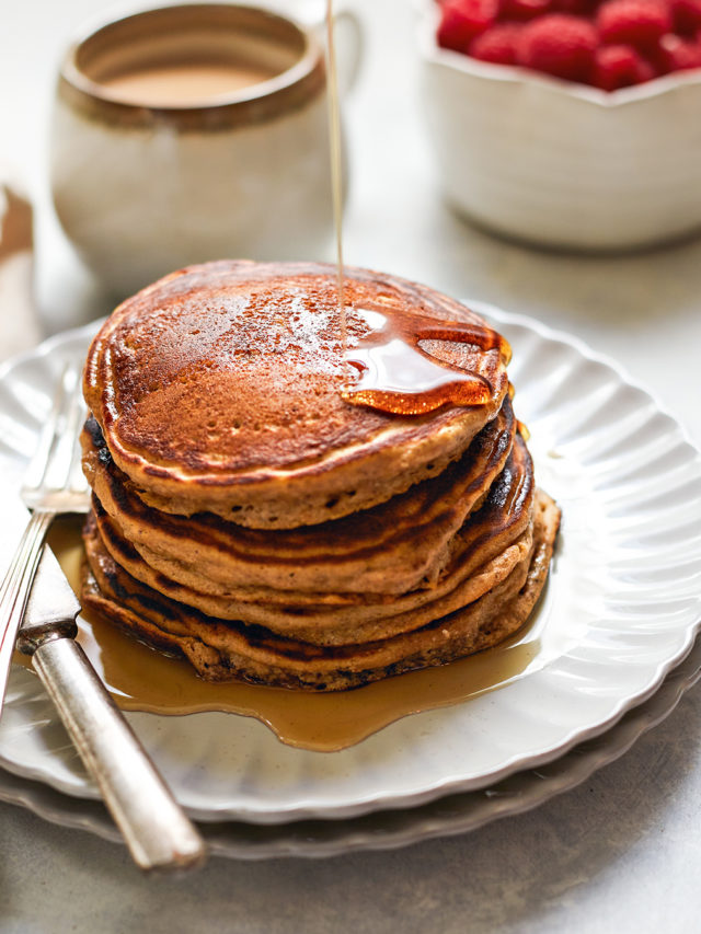 maple syrup drizzling on a plate of multigrain pancakes