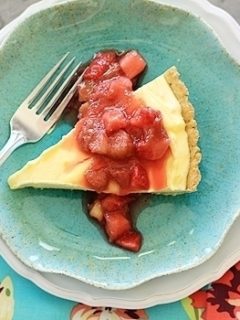 Overhead view of a slice of lemon curd tart topped with strawberry rhubarb compote on a blue plate.