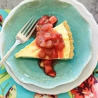 Overhead view of a slice of lemon curd tart topped with strawberry rhubarb compote on a blue plate.