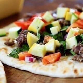 flat bread pizza with zucchini, sausage, peppers, and basil