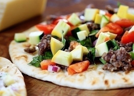 flat bread pizza with zucchini, sausage, peppers, and basil