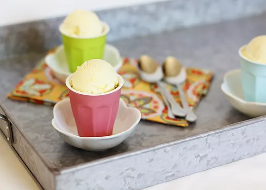 two glasses of lemon ice cream next to spoons