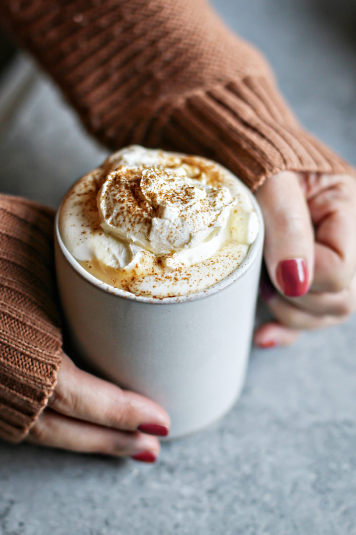 photo of woman holding a mug of pumpkin hot chocolate with vanilla whipped cream