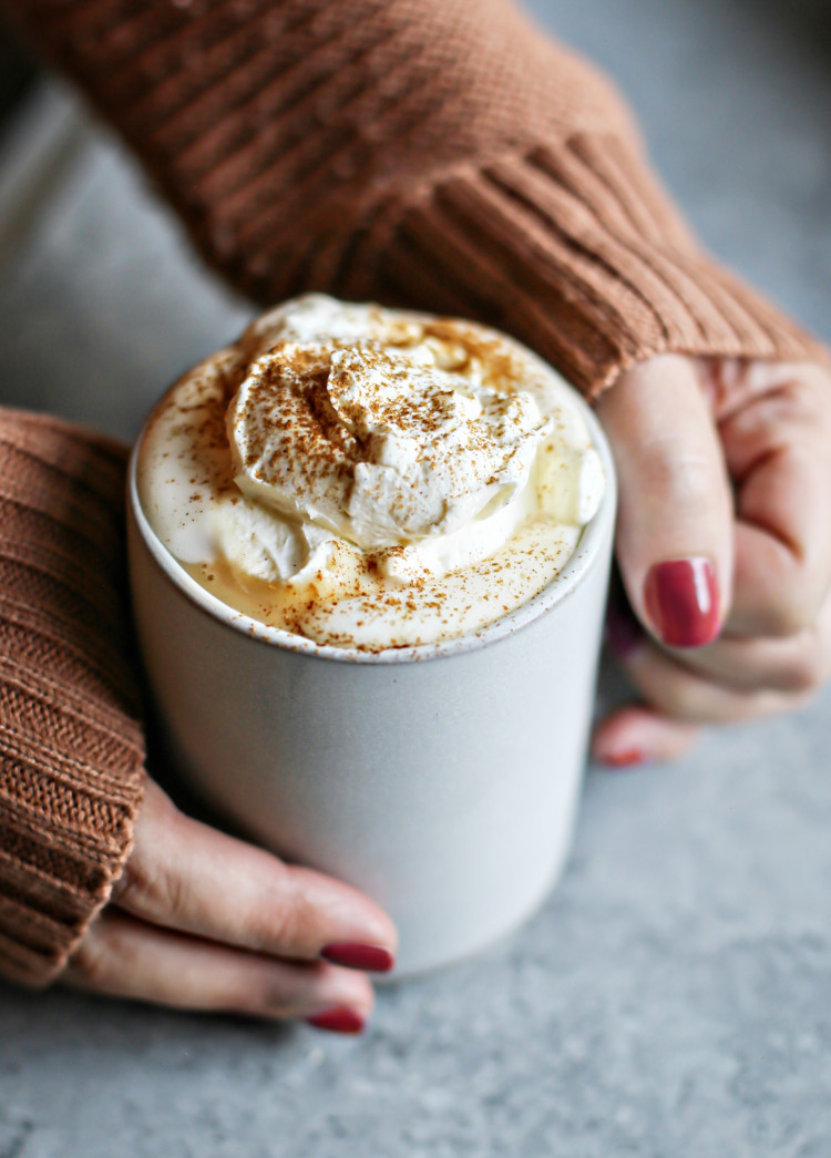 photo of woman holding a mug of pumpkin hot chocolate with vanilla whipped cream