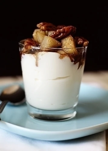 maple and cardamom spiced pear compote with pecans on top of greek yogurt in a glass