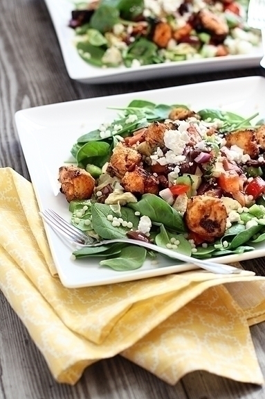 A tandoori chicken salad on a white plate with a fork. 