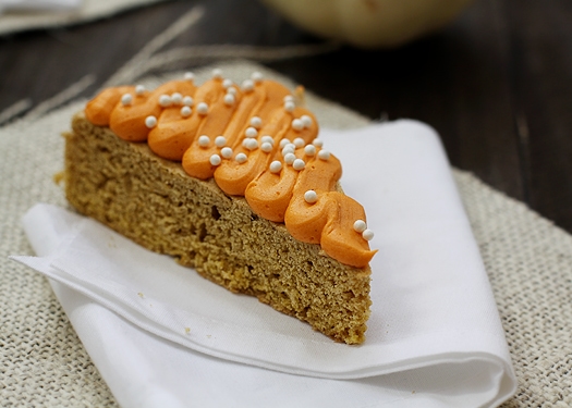 Pumpkin cookie bars topped with frosting on white napkins. 