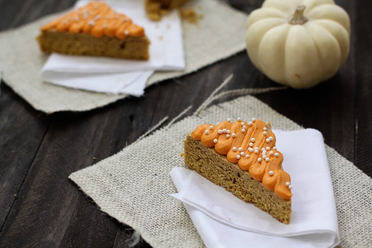 Pumpkin cookie bars topped with frosting on white napkins.