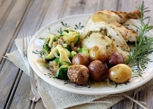 rosemary roasted chicken pieces on a plate with roasted potatoes and brussels sprouts 