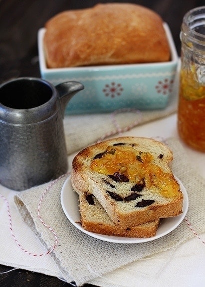 Two slices of orange chocolate swirl bread on a white plate. A mini loaf rests in the background. 