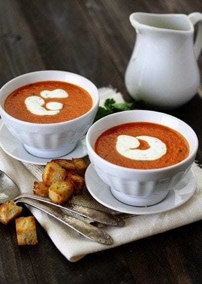 two bowls of roasted red pepper soup swirled with cilantro cream