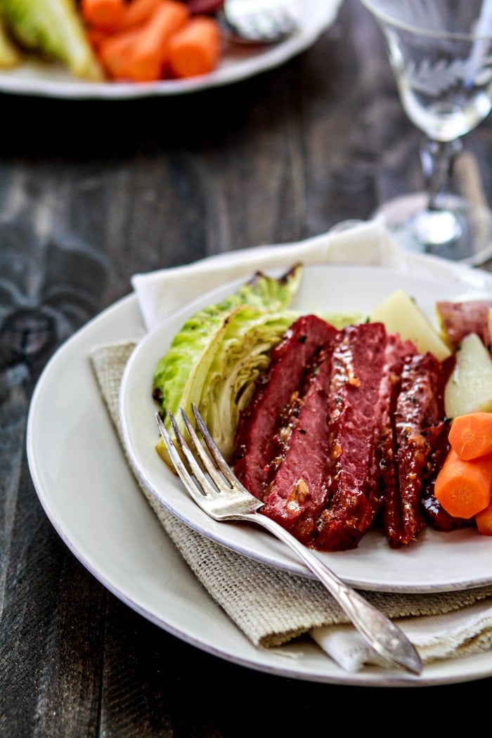 sliced glazed corned beef on plate with vegetables