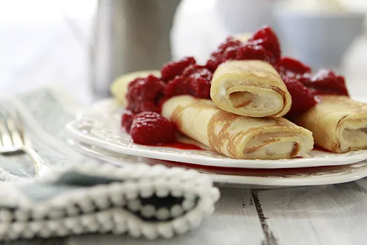 orange raspberry dessert crepes on white plates