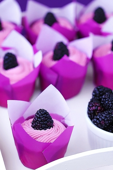 easy lemon cupcakes topped with blackberry buttercream frosting in paper liners 