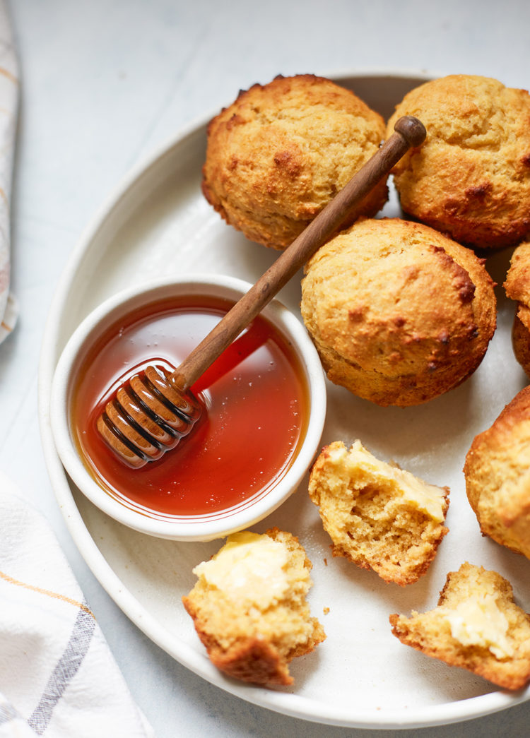 cornbread honey muffins on a plate with a bowl of honey
