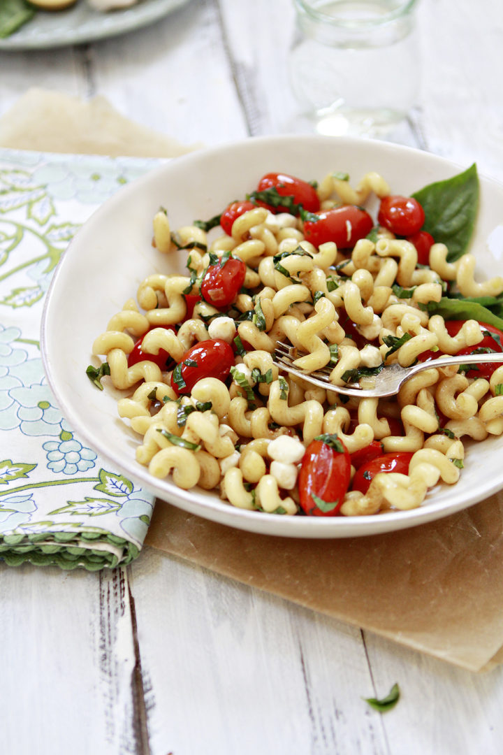 photo of a table set with bowl of pasta caprese