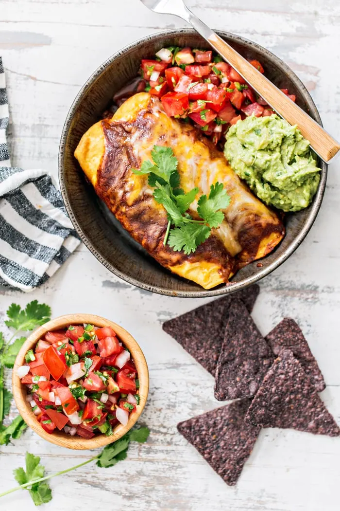 homemade enchiladas in bowl topped with chili gravy enchilada sauce with guac and salsa