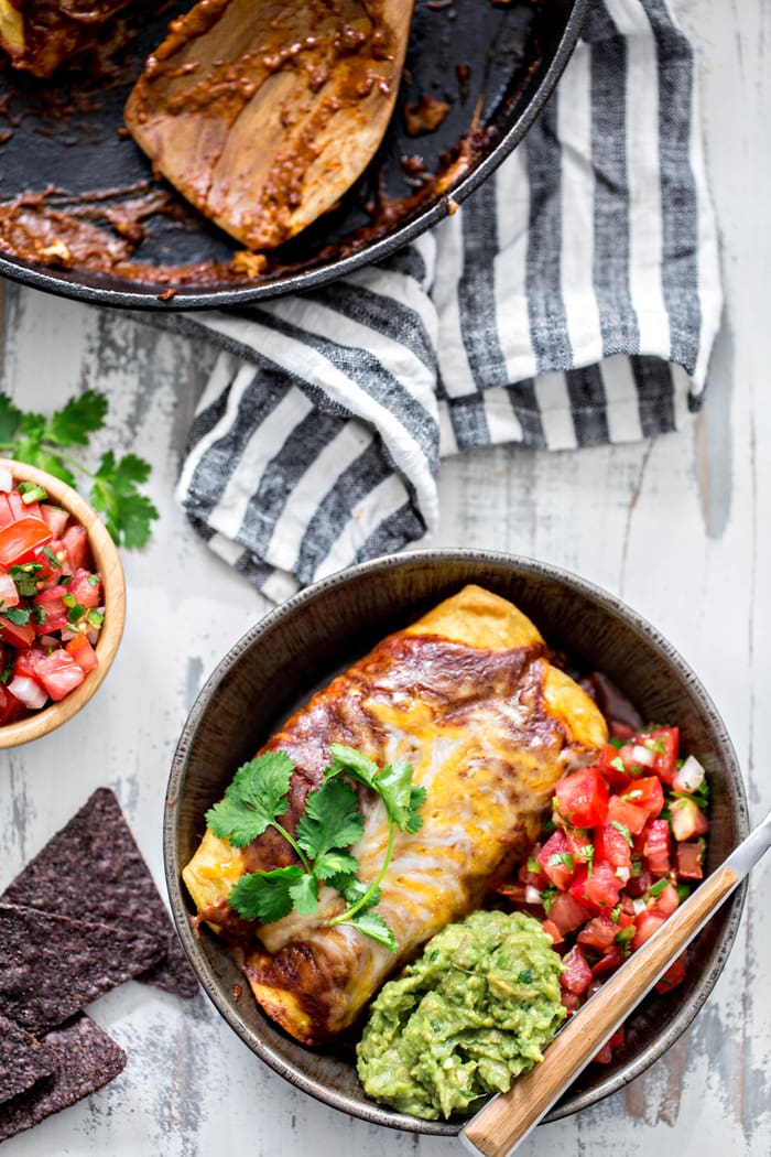 homemade chicken enchiladas in bowl with guacamole and pice de gallo