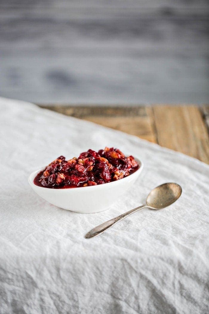 cranberry sauce with orange juice in white serving dish next to spoon