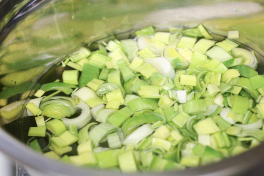 Chopped leeks in a metal bowl with water. 