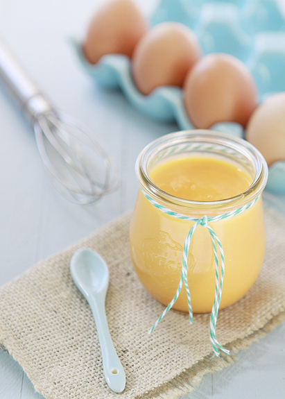 photo of orange curd in a jar with a small spoon