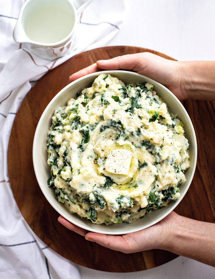 woman holding a bowl of Easy Colcannon Recipe (Irish Mashed Potatoes with Leeks and Kale)