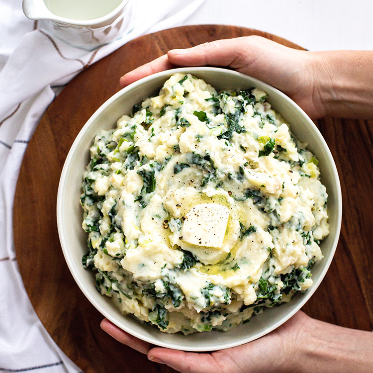 woman holding a bowl of Easy Colcannon Recipe (Irish Mashed Potatoes with Leeks and Kale)