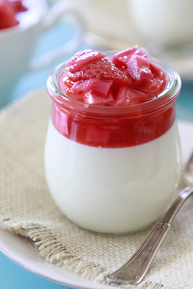 A glass jar of vanilla bean panna cotta topped with strawberry rhubarb compote 