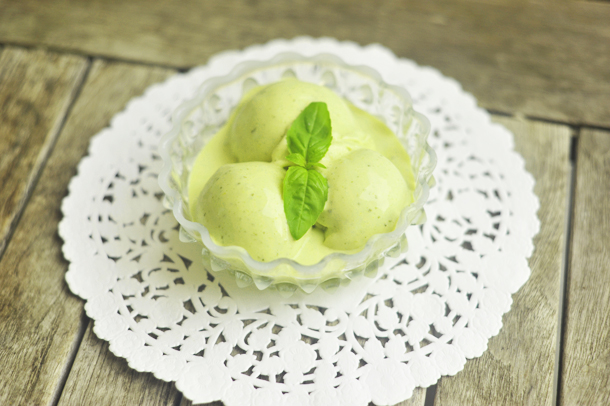 a photo of lemon basil ice cream in a bowl on a wooden table