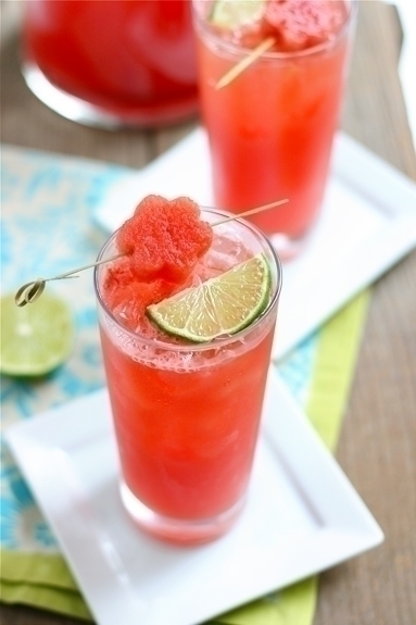 2 glasses of watermelon limeade on a table with plates