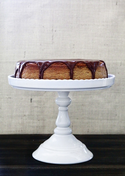 A chocolate pumpkin cheesecake on a white cake stand. 