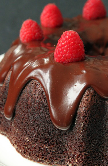 A chocolate raspberry bundt cake topped with ganache and fresh berries 