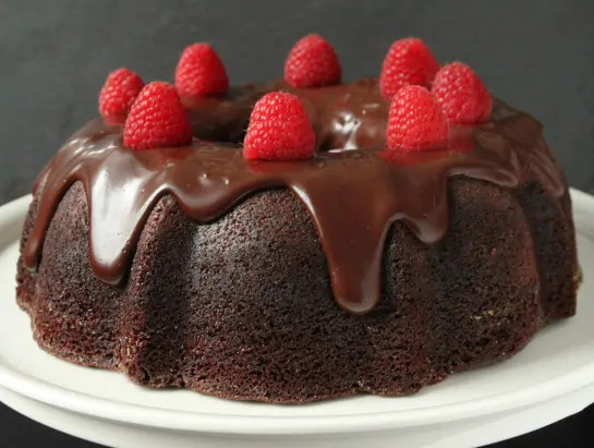 A chocolate raspberry bundt cake topped with ganache and fresh berries 