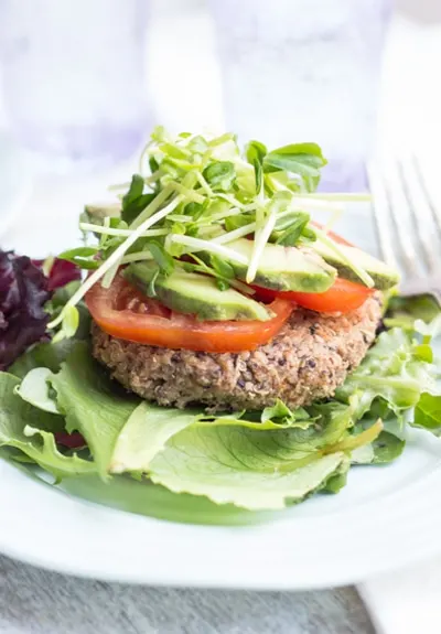 Black Bean Quinoa Burger on lettuce leaf with vegetarian toppings