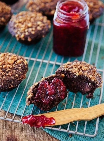 photo of this dark chocolate muffin recipe on a cooling rack with a jar of jam