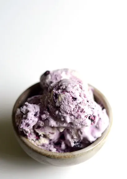 blueberry cheesecake ice cream in a brown bowl on a white background