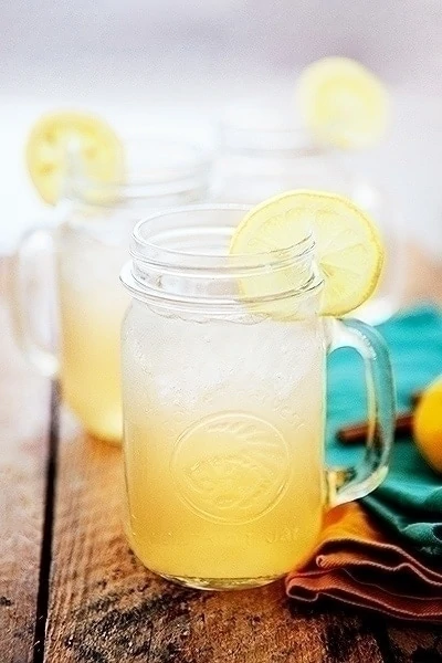 glass jars filled with a recipe for spicy lemonade. the glasses of spiced lemonade is garnished with lemon slices