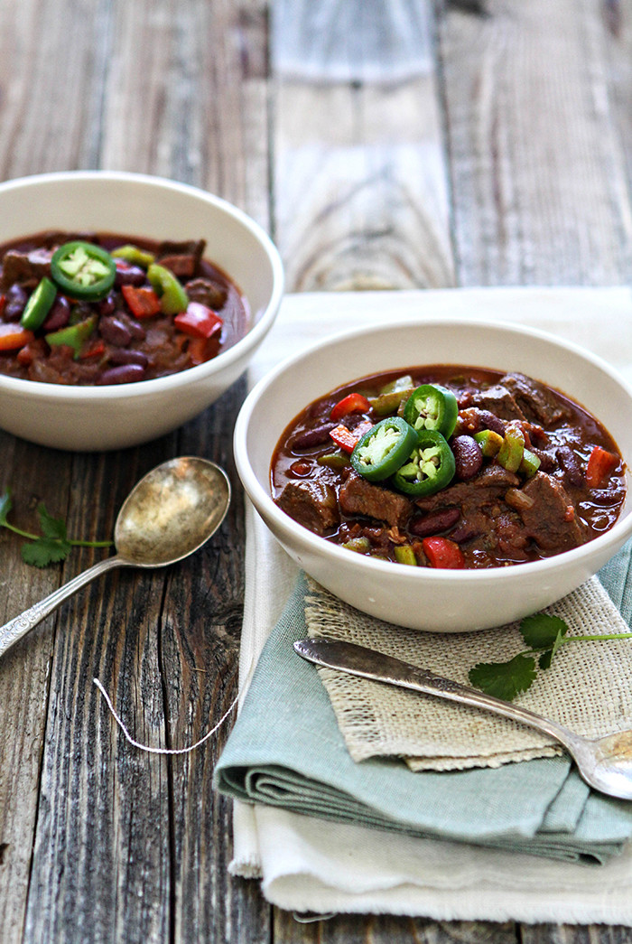 two bowls of chili with beef short ribs on a rustic wooden table