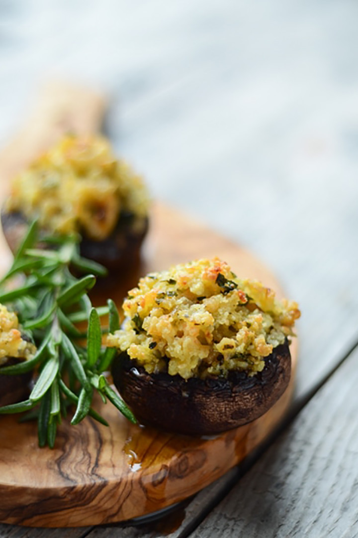 shrimp stuffed mushrooms on a wooden board with fresh rosemary sprigs