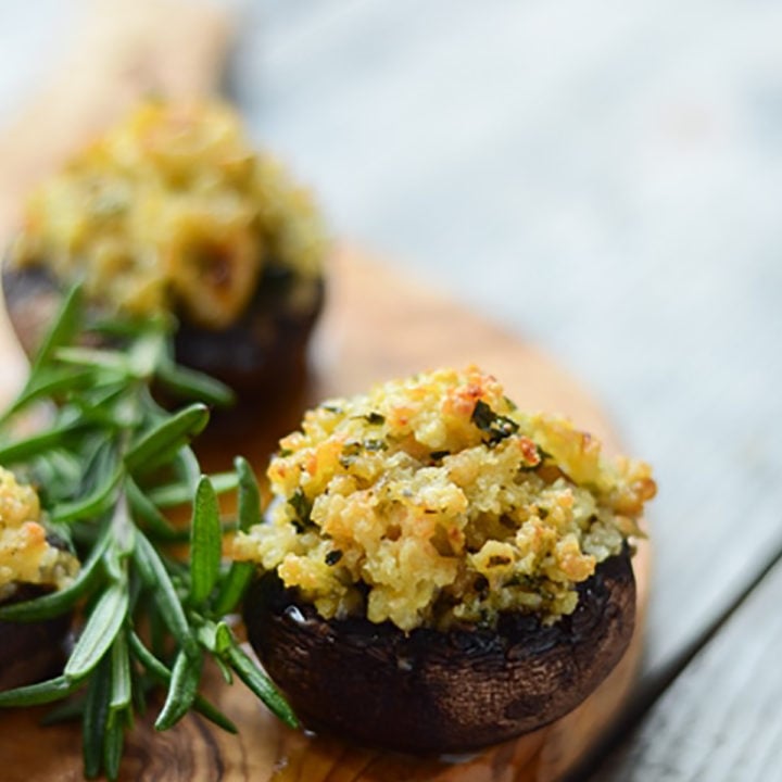 shrimp stuffed mushrooms on a wooden board with fresh rosemary sprigs